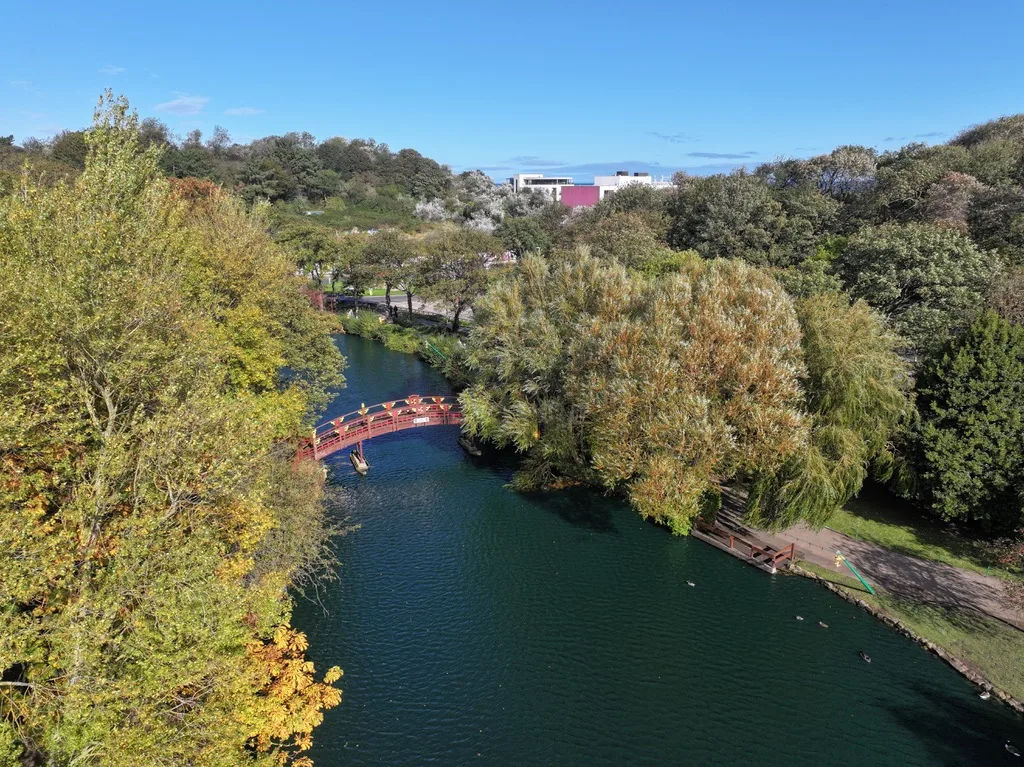 Peasholm Park bridge from above in Scarborough showing the lake, trees and surrounding greenery on a clear day