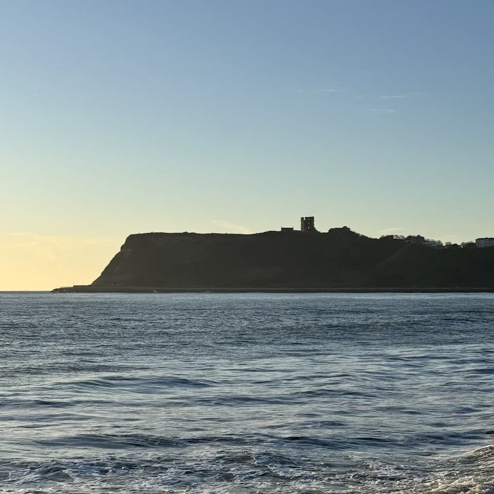 North Bay Scarborough at sunrise with calm sea and castle headland on the Yorkshire coast